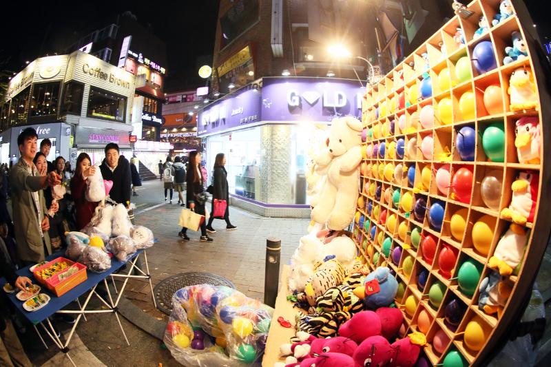 Hongdae streets illuminated at night with shops, signs, pedestrians and nightlife activities outside clubs